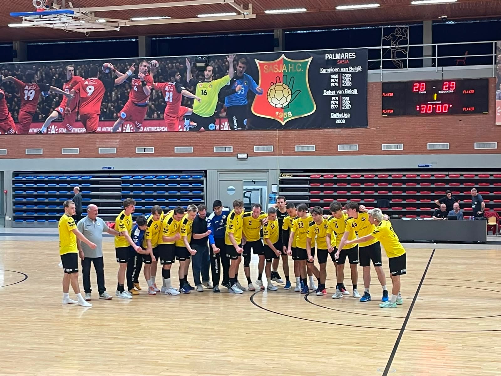 🔥 HEREN 2 WINT THRILLER TEGEN SASJA 🔥

Afgelopen zaterdag mochten de Heren Liga weer op bezoek bij @sasjahc in Hoboken. De Antwerpenaars zijn ondertussen een vertrouwde tegenstander en staan altijd garant voor stevige handbalpartijen.

Met een aangepast defensief plan en het voornemen om een verschroeiend tempo op te leggen, begonnen onze jongens vol goesting. De eerste minuten ging het voortdurend snel over en weer, zonder dat één ploeg afstand kon nemen.

Dat het tempo hoog lag, heeft ook uw verslaggever – die op het veld stond – geweten. Na enkele minuten moest hij met het schaamrood op de wangen vaststellen dat hij dit geen volledige helft, laat staan 60 minuten, zou volhouden. Gelukkig kon Don Bosco rekenen op een volle bank en werd er lustig doorgewisseld.

Tegen het einde van de eerste helft profiteerde Sasja enkele keren klinisch van Gentse slordigheden. Ruststand: 17-13.

De Liga-boys waren echter allerminst onder de indruk en begonnen met hetzelfde mes tussen de tanden aan de tweede helft. Toch bleef Sasja overeind. Met nog 12 minuten op de klok en een 28-24 stand leek de wedstrijd stilaan definitief de kant van de thuisploeg op te draaien.

Maar toen begon de Gentse remonte.

Aangevuurd door een zeer sterke Rahul in doel knabbelden onze heren punt per punt van de achterstand. Bartel en Arne organiseerden de verdediging, terwijl Karel zijn verantwoordelijkheid nam in aanval.

Met zijn vierde treffer in de laatste 10 minuten bracht Karel DB Gent op iets meer dan een minuut van het einde voor het eerst op voorsprong: 28-29.

Na een mislukte laatste Gentse aanval kreeg Sasja met nog 15 seconden op de klok dé kans op de gelijkmaker. Eén tegenaanvalpas later stond een Antwerpenaar oog in oog met Rahul.

Maar dit was buiten onze doelman gerekend.

🧱 IJskoud ranselde Rahul de ultieme poging uit zijn doel en sleepte zo een bijzonder hardbevochten en deugddoende overwinning uit de brand.

Eindstand: 28-29. 💪🔥